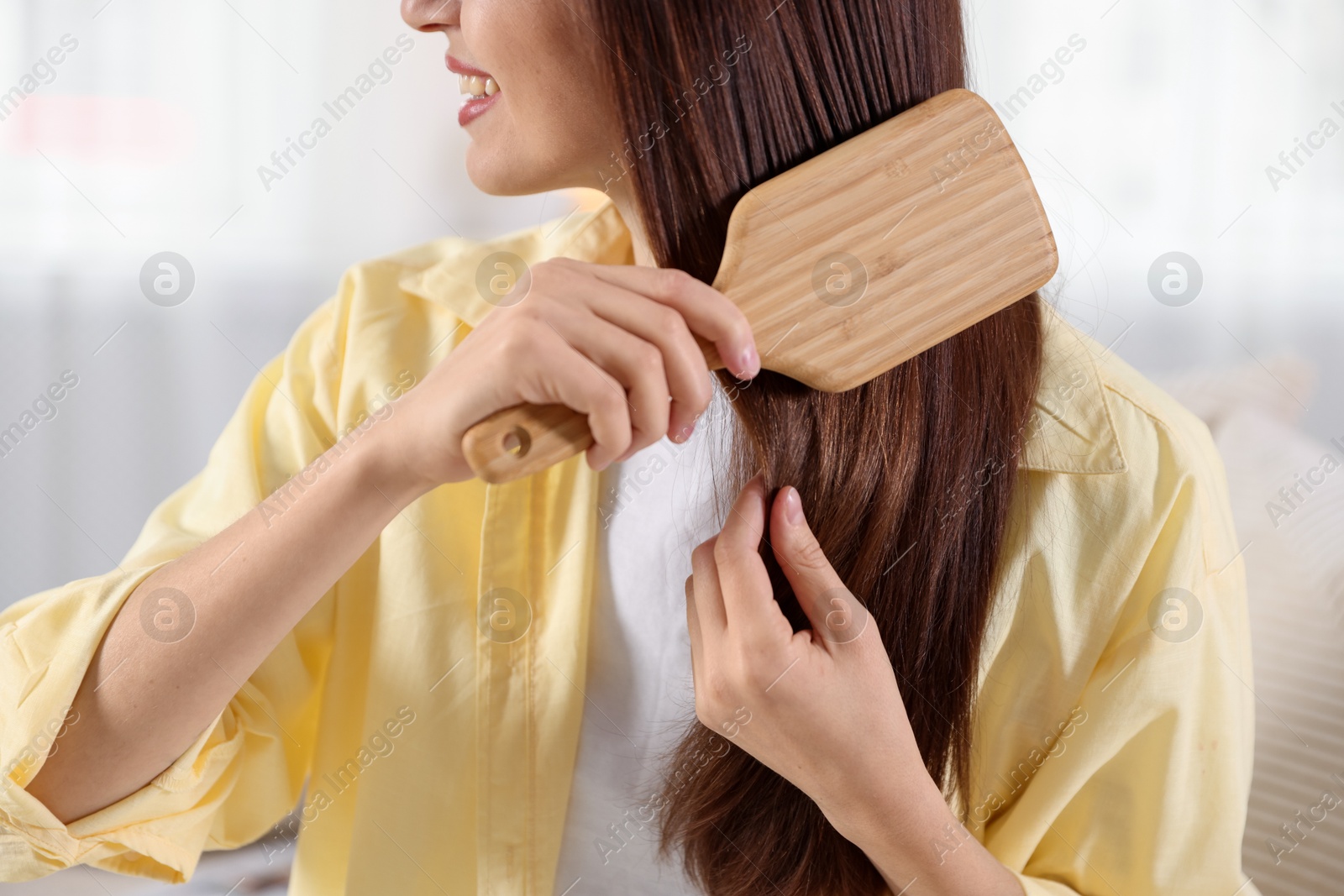 Photo of Woman brushing her hair at home, closeup