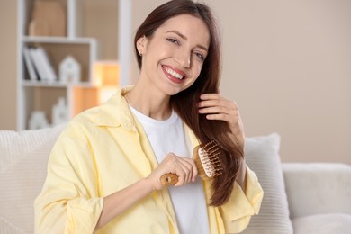 Smiling woman brushing her hair at home