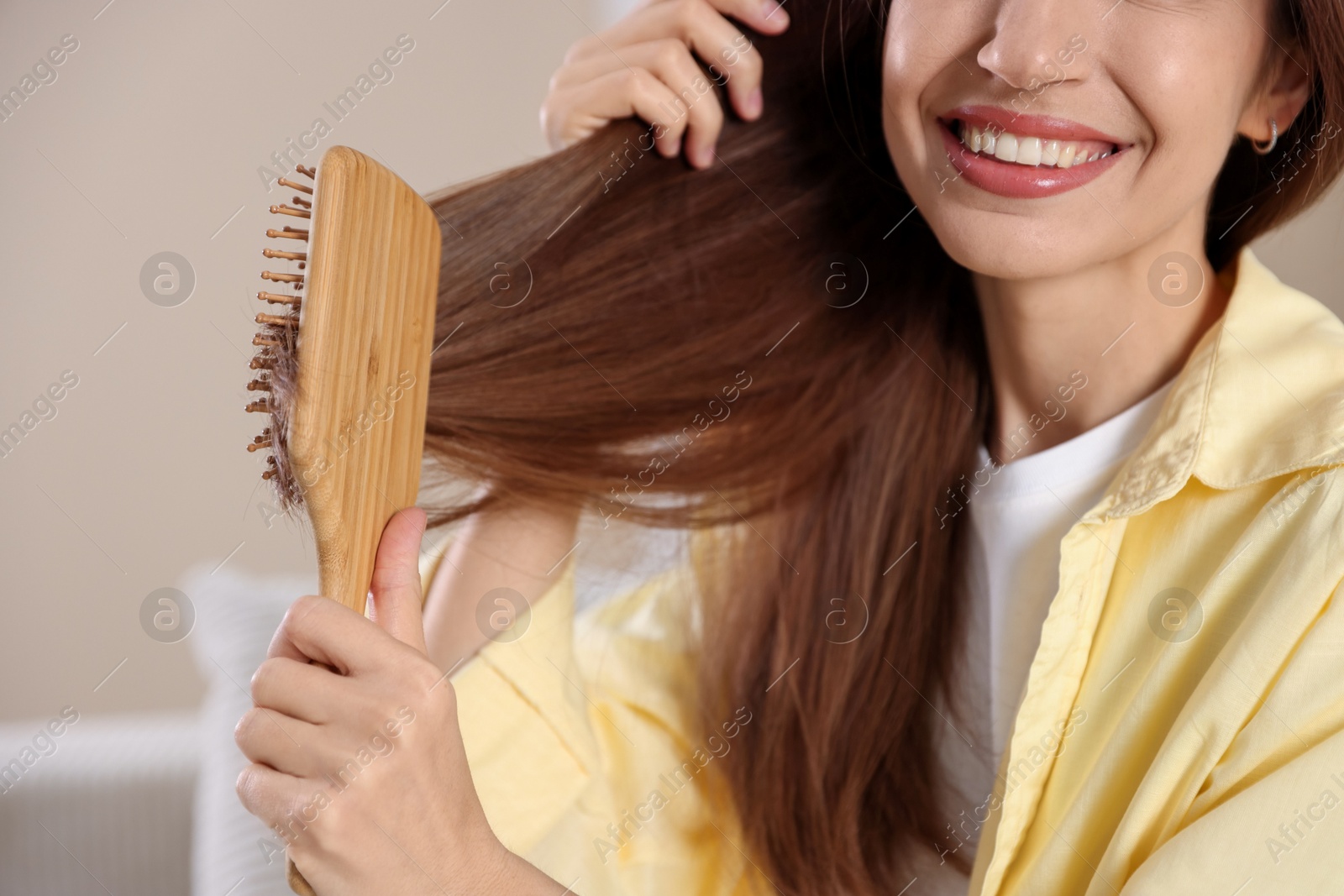 Photo of Smiling woman brushing her hair at home, closeup