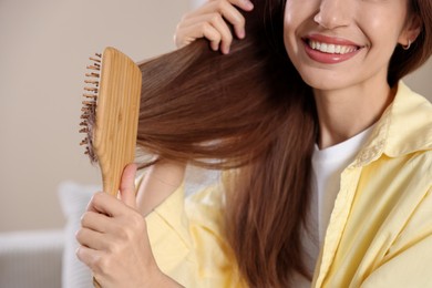 Smiling woman brushing her hair at home, closeup