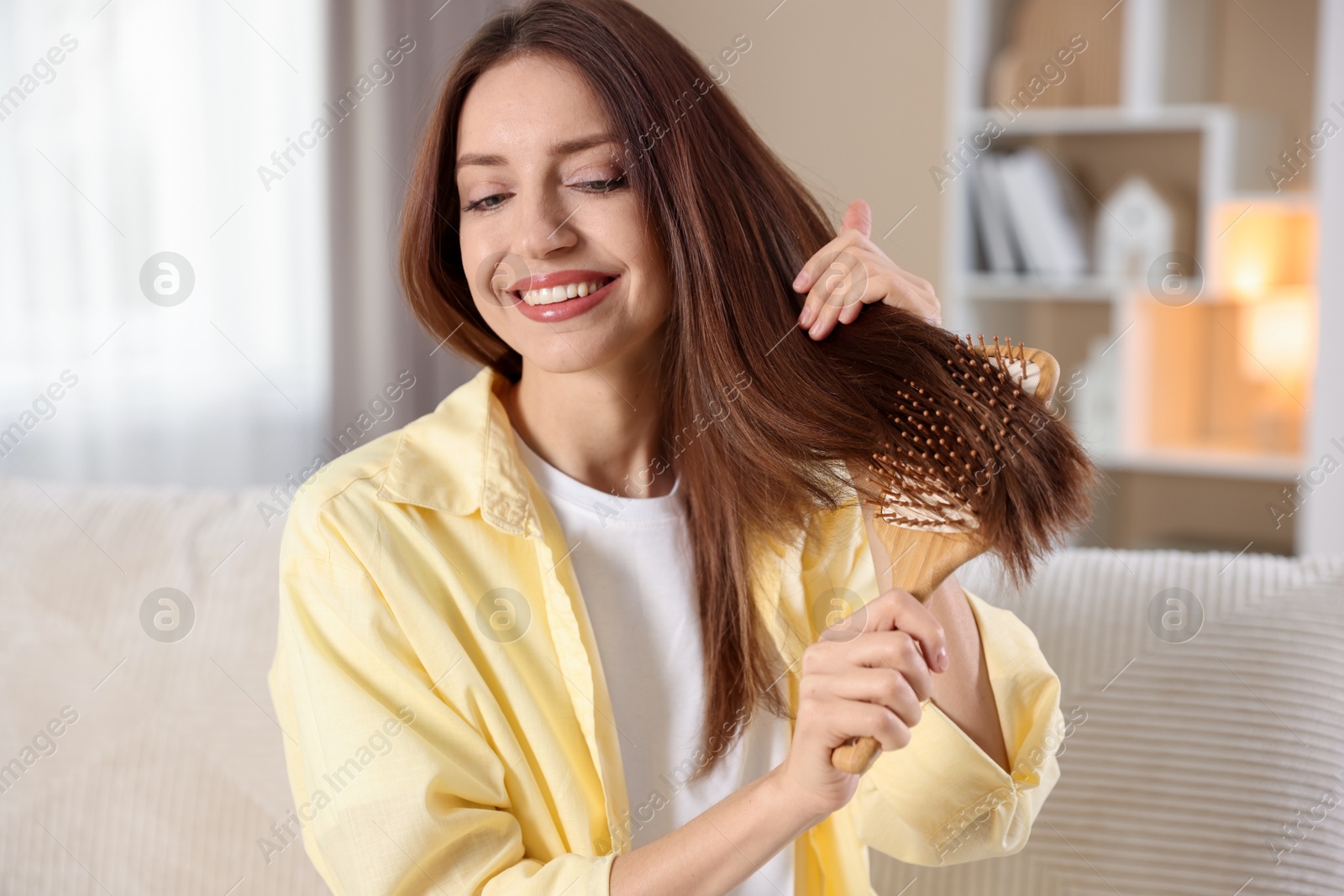 Photo of Smiling woman brushing her hair at home