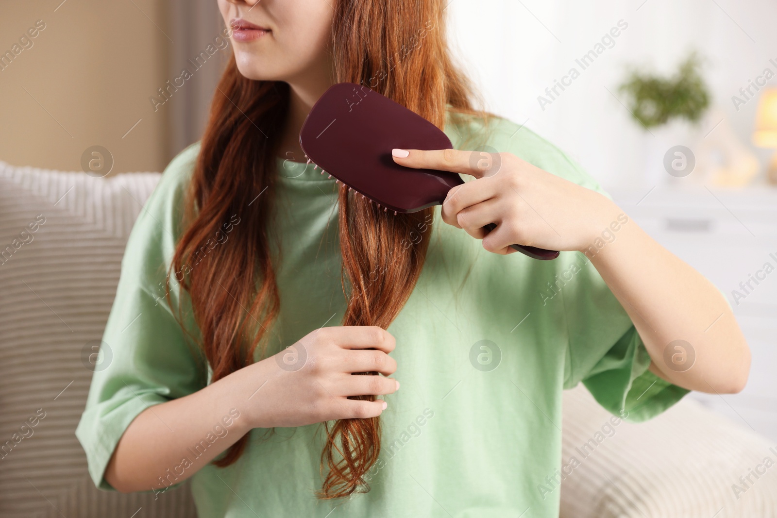 Photo of Teenage girl brushing her hair at home, closeup