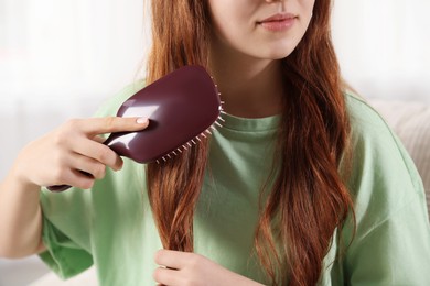 Photo of Teenage girl brushing her hair at home, closeup