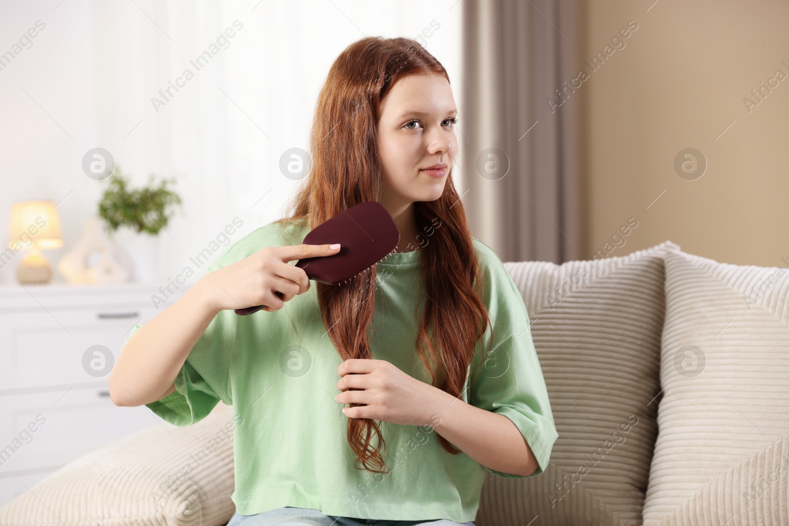 Photo of Beautiful teenage girl brushing her hair at home