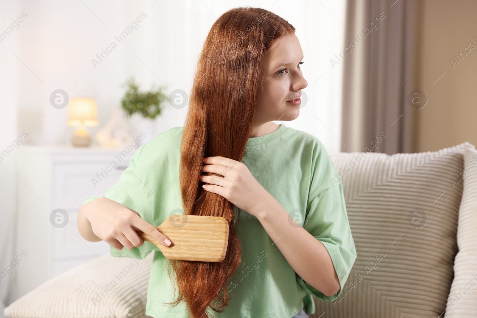 Photo of Beautiful teenage girl brushing her hair at home