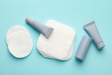 Photo of Clean cotton pads and cosmetic products on light blue background, flat lay