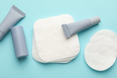 Photo of Clean cotton pads and cosmetic products on light blue background, flat lay