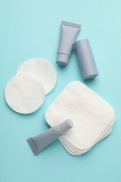 Photo of Clean cotton pads and cosmetic products on light blue background, flat lay