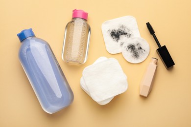 Photo of Clean and dirty cotton pads, mascara, micellar water on beige background, flat lay