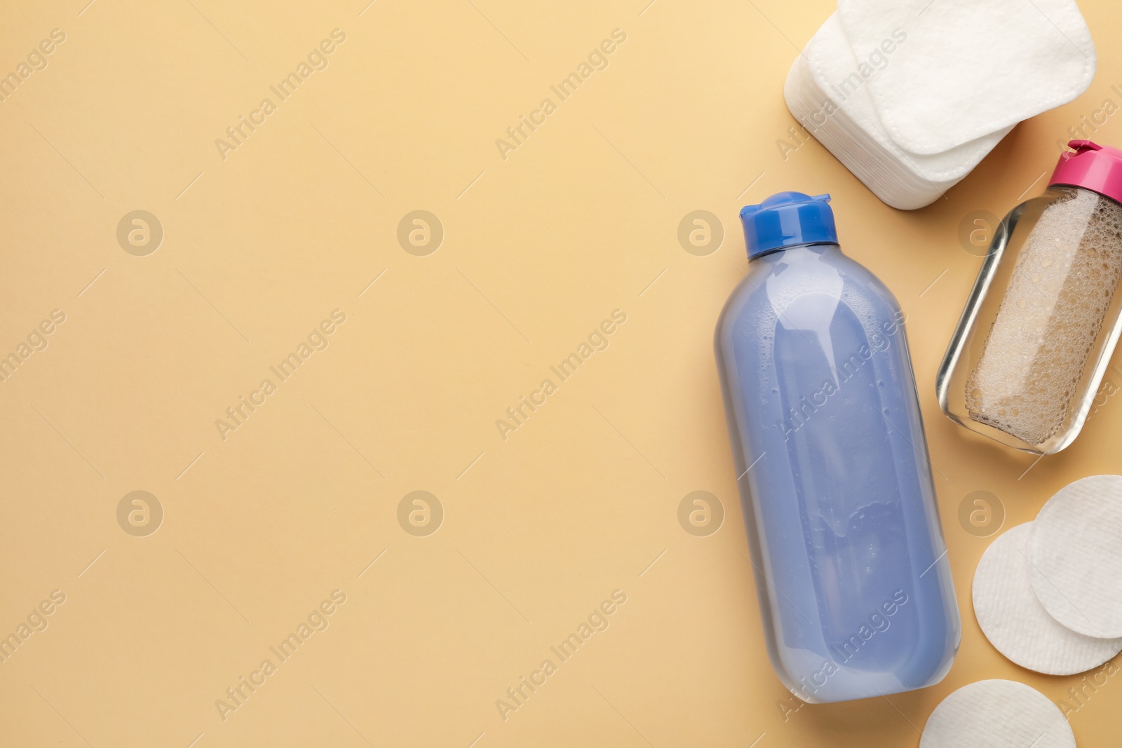 Photo of Clean cotton pads and micellar water on beige background, flat lay. Space for text