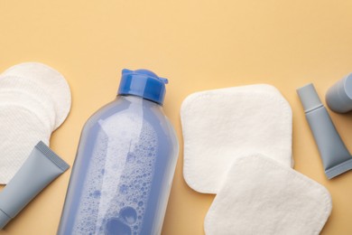 Photo of Clean cotton pads and cosmetic products on beige background, flat lay