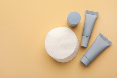 Photo of Clean cotton pads and cosmetic products on beige background, flat lay. Space for text