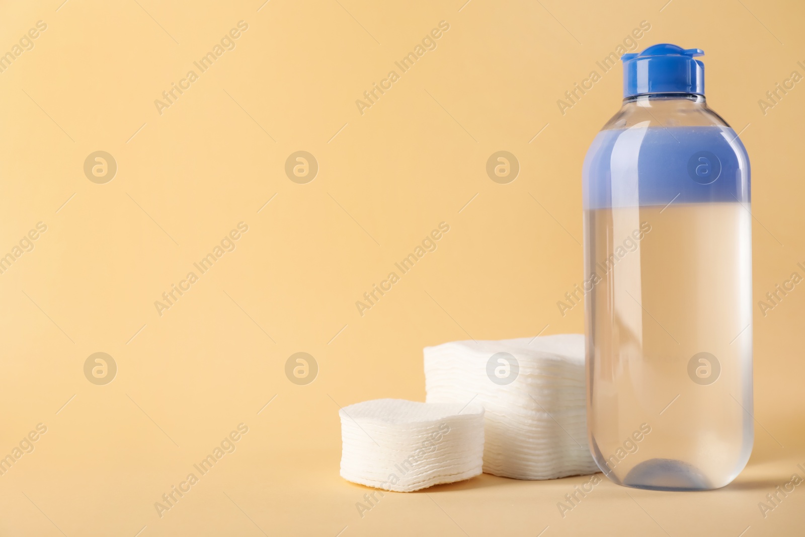 Photo of Clean cotton pads and micellar water on beige background. Space for text