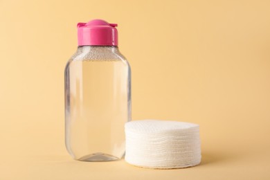 Photo of Clean cotton pads and micellar water on beige background, closeup. Space for text