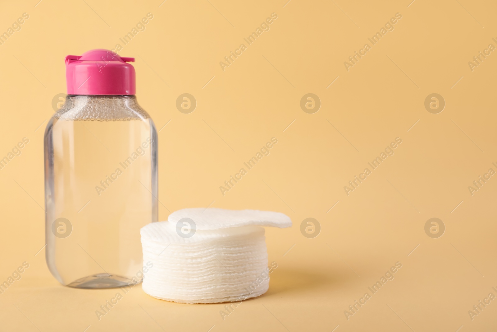 Photo of Clean cotton pads and micellar water on beige background. Space for text