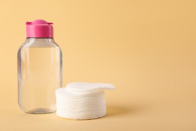 Photo of Clean cotton pads and micellar water on beige background. Space for text