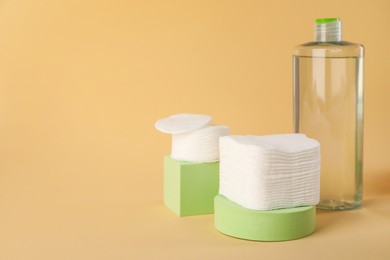 Photo of Clean cotton pads and micellar water on beige background. Space for text