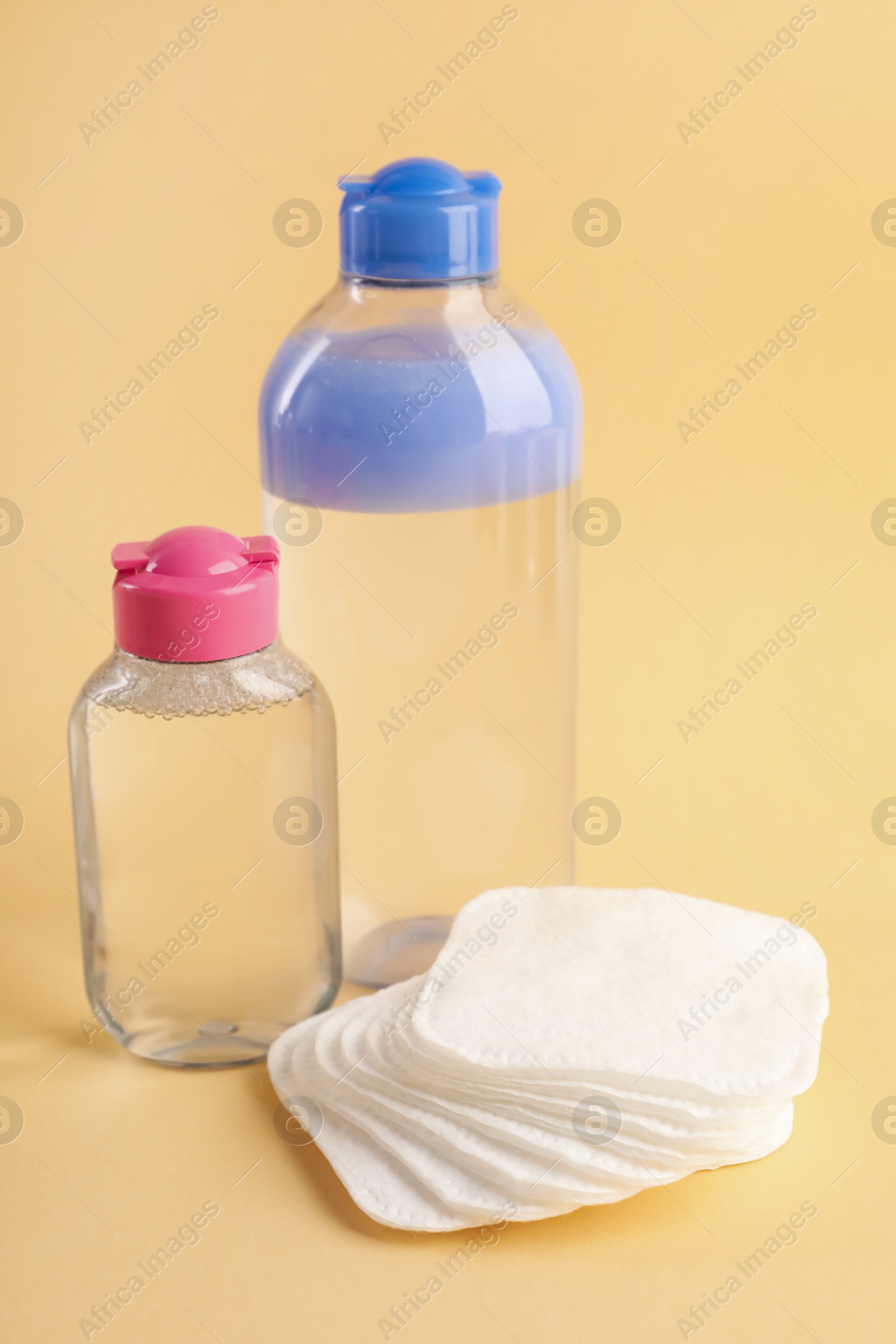 Photo of Clean cotton pads and micellar water on beige background