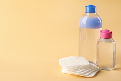 Photo of Clean cotton pads and micellar water on beige background. Space for text