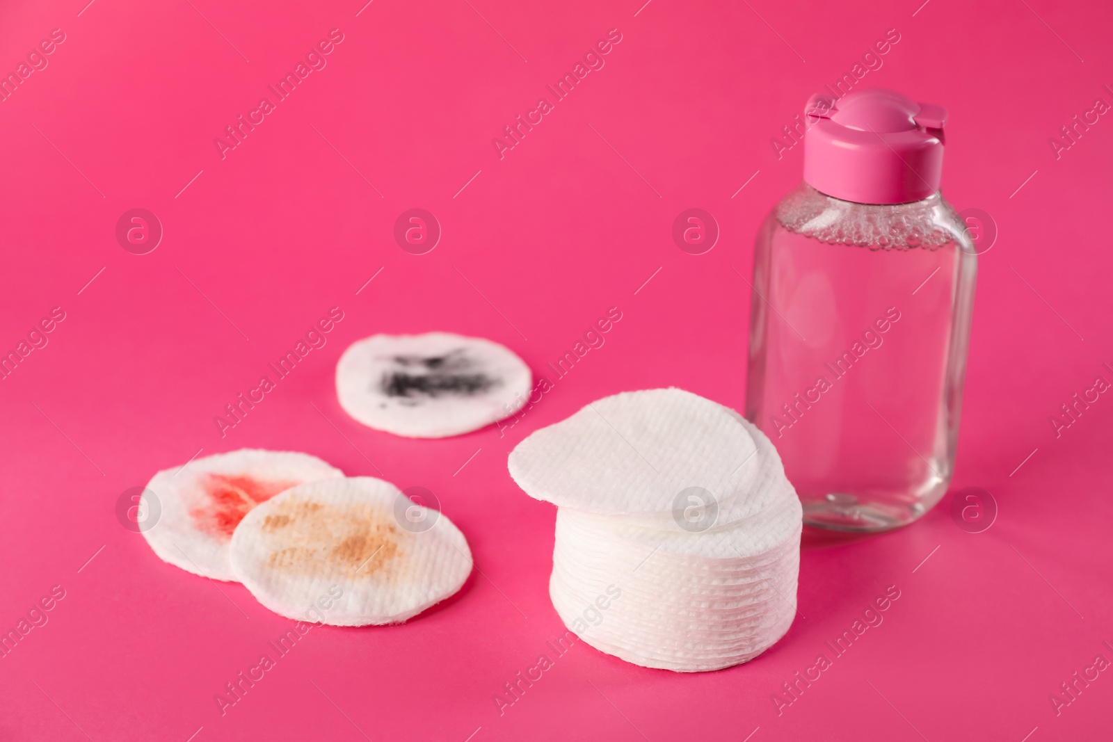 Photo of Clean and dirty cotton pads with micellar water on pink background, closeup. Space for text