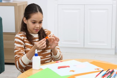 Photo of Girl making art project at table indoors. Space for text