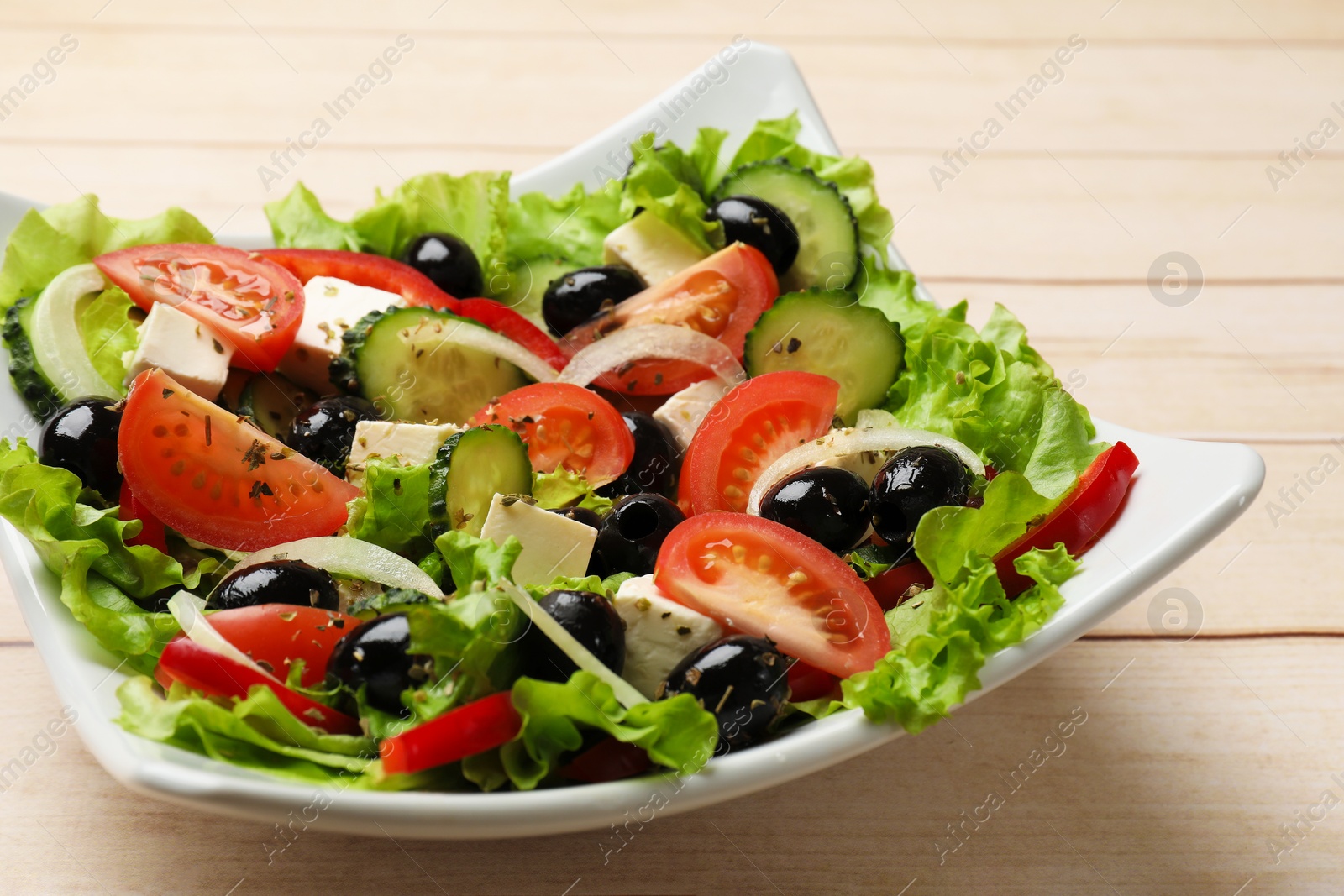 Delicious fresh Greek salad on white wooden table, closeup Photo of Delicious fresh Greek salad on white wooden table, closeup