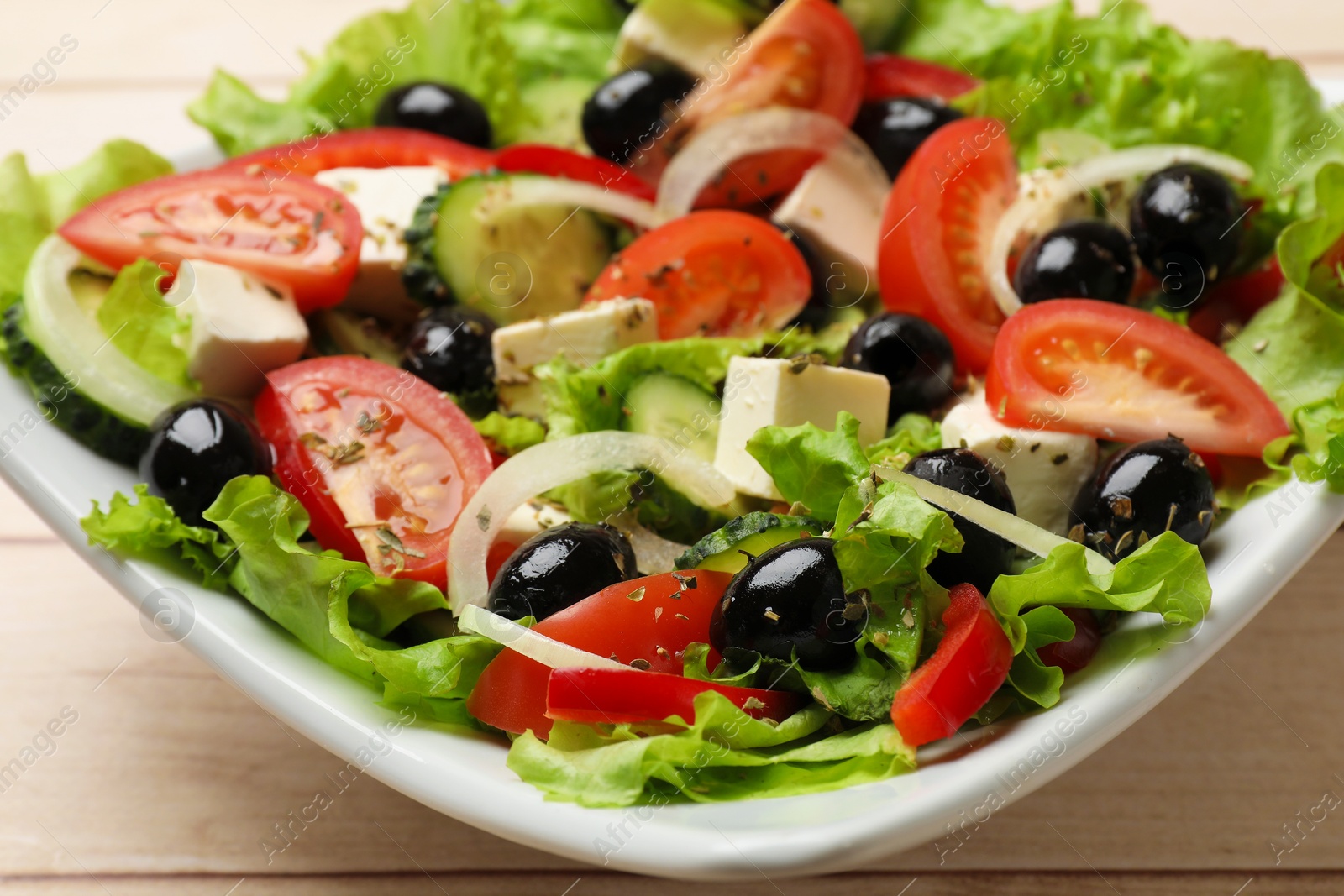 Delicious fresh Greek salad on white wooden table, closeup Photo of Delicious fresh Greek salad on white wooden table, closeup