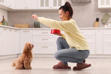 Photo of Smiling owner feeding her cute pet in kitchen