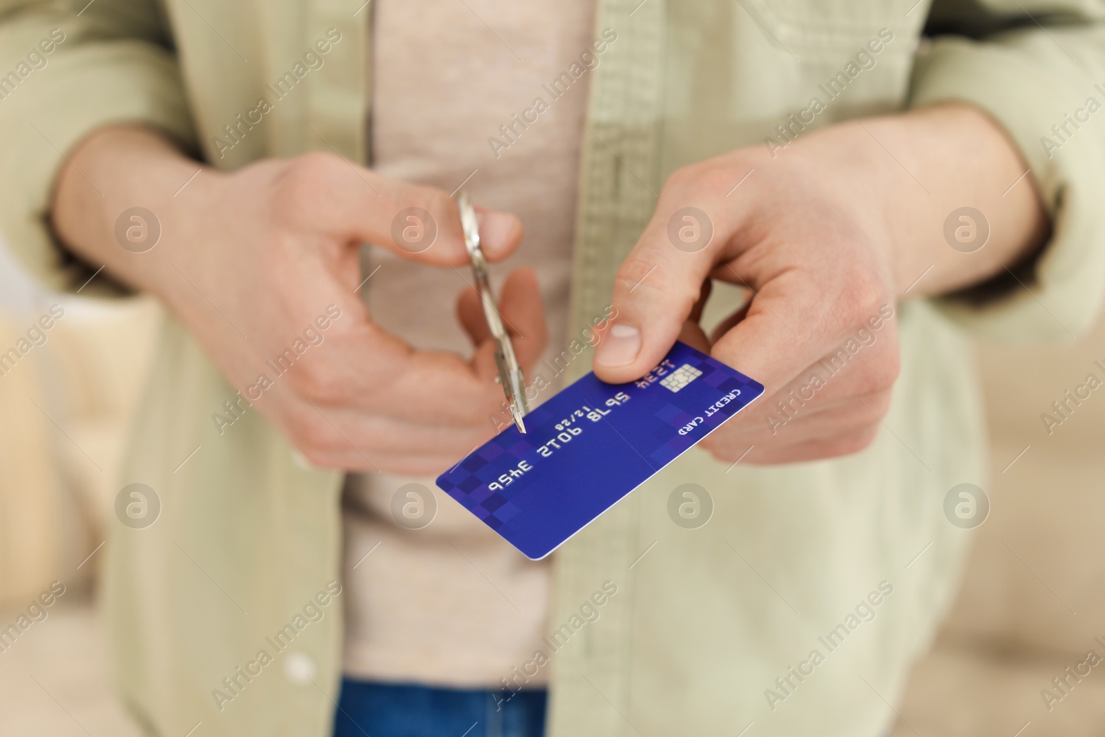 Photo of Man cutting his credit card indoors, closeup