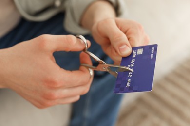 Photo of Man cutting his credit card indoors, closeup