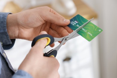 Photo of Man cutting his credit card indoors, closeup