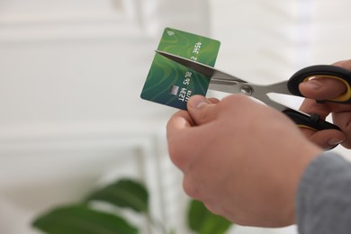 Photo of Man cutting his credit card indoors, closeup