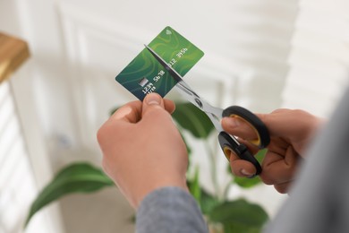 Photo of Man cutting his credit card indoors, closeup