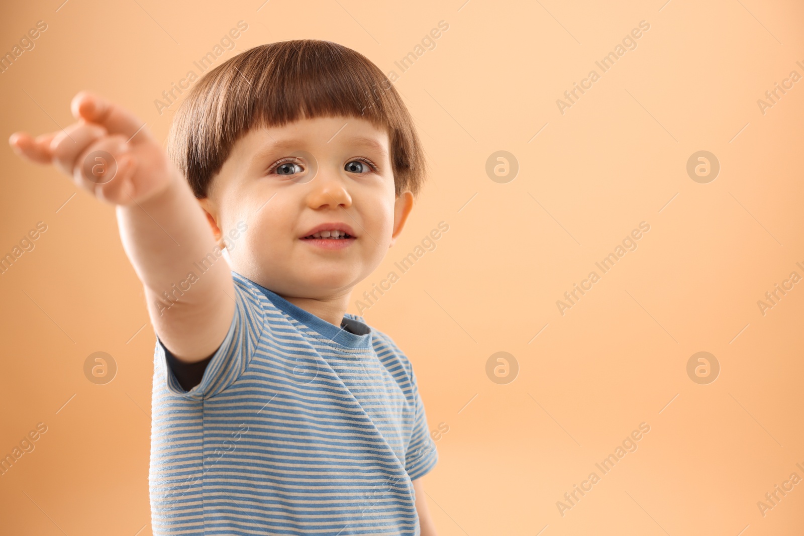 Photo of Portrait of smiling little boy on beige background. Space for text