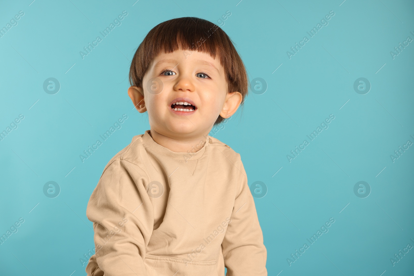 Photo of Portrait of happy little boy on light blue background