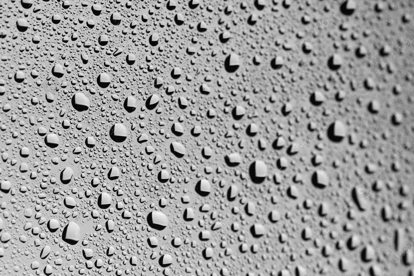 Photo of Water drops on grey glass surface, closeup