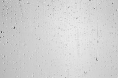 Photo of Water drops on light grey glass surface, top view