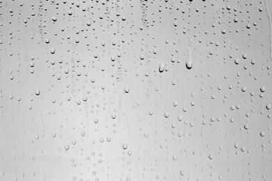 Water drops on light grey glass surface, top view