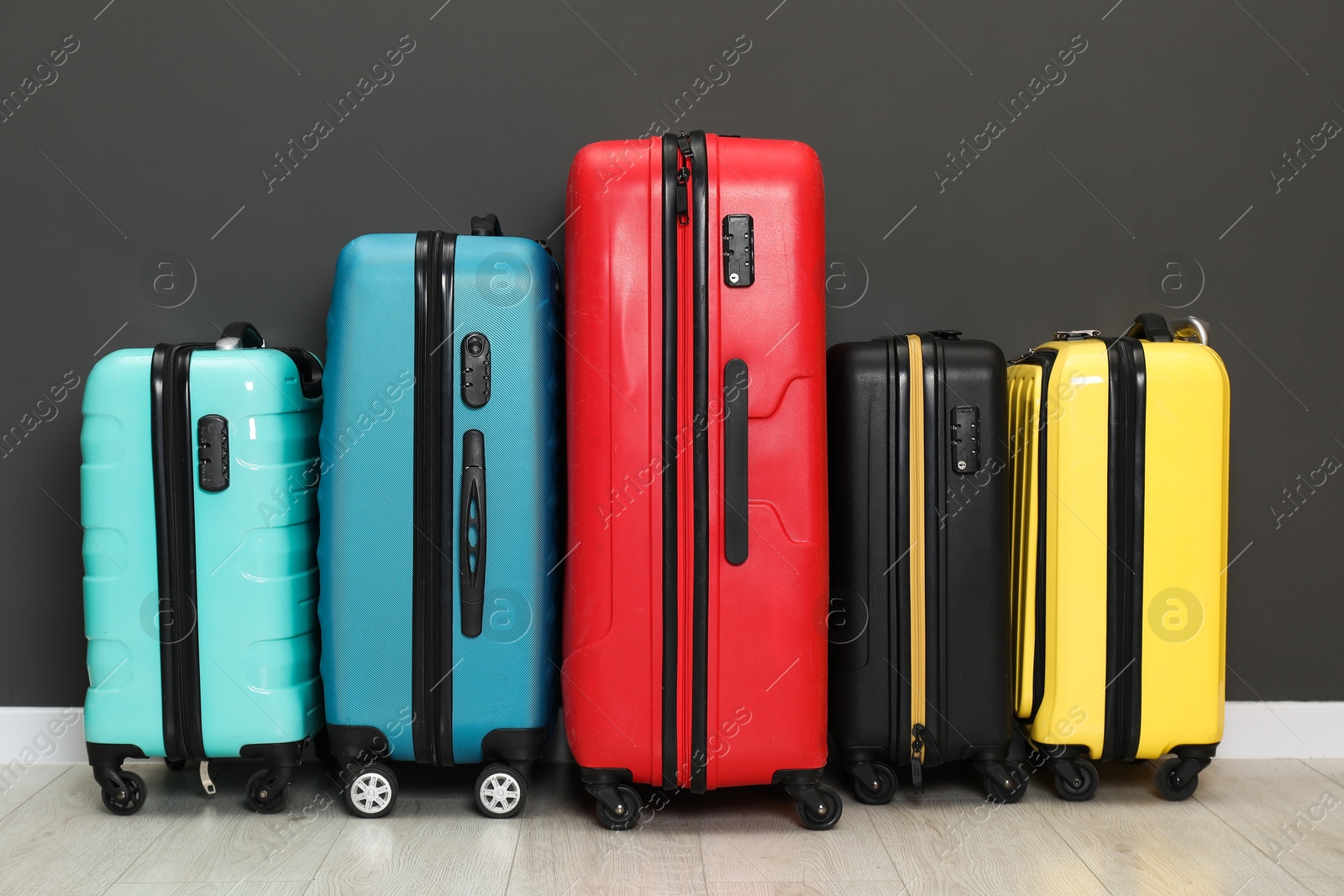 Photo of Colorful suitcases on floor near black wall