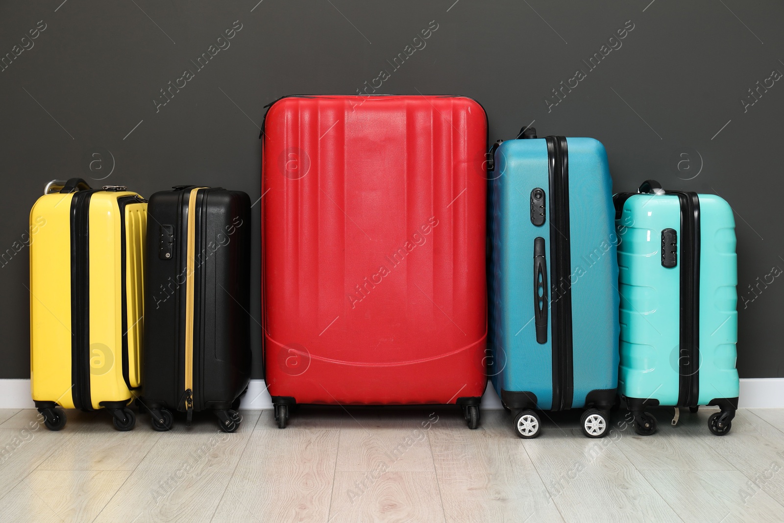 Photo of Colorful suitcases on floor near black wall