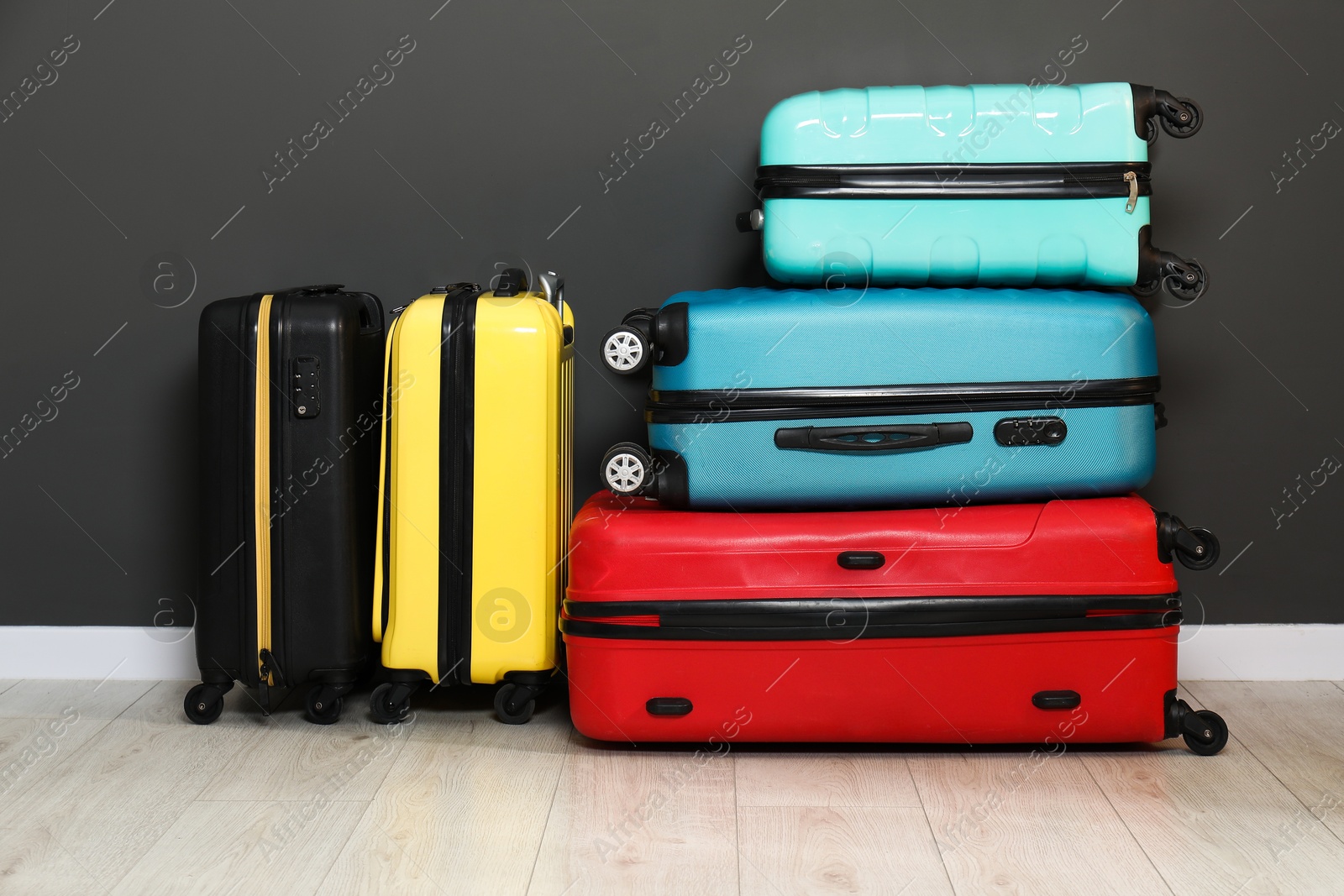 Photo of Colorful suitcases on floor near black wall