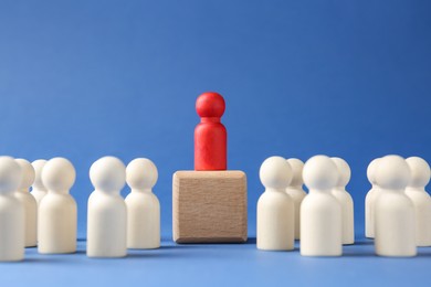 Photo of Competition concept. Human figure on wooden cube and other ones behind against blue background