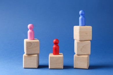 Photo of Competition concept. Human figures on wooden cubes against blue background