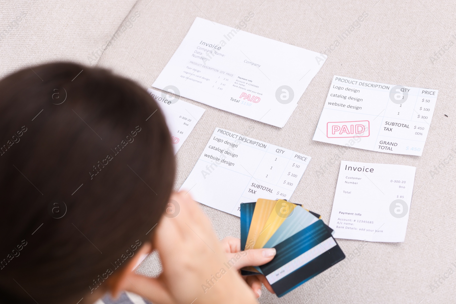 Photo of Paying bills. Woman with different invoices and credit cards on couch at home, closeup