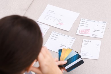 Photo of Paying bills. Woman with different invoices and credit cards on couch at home, closeup