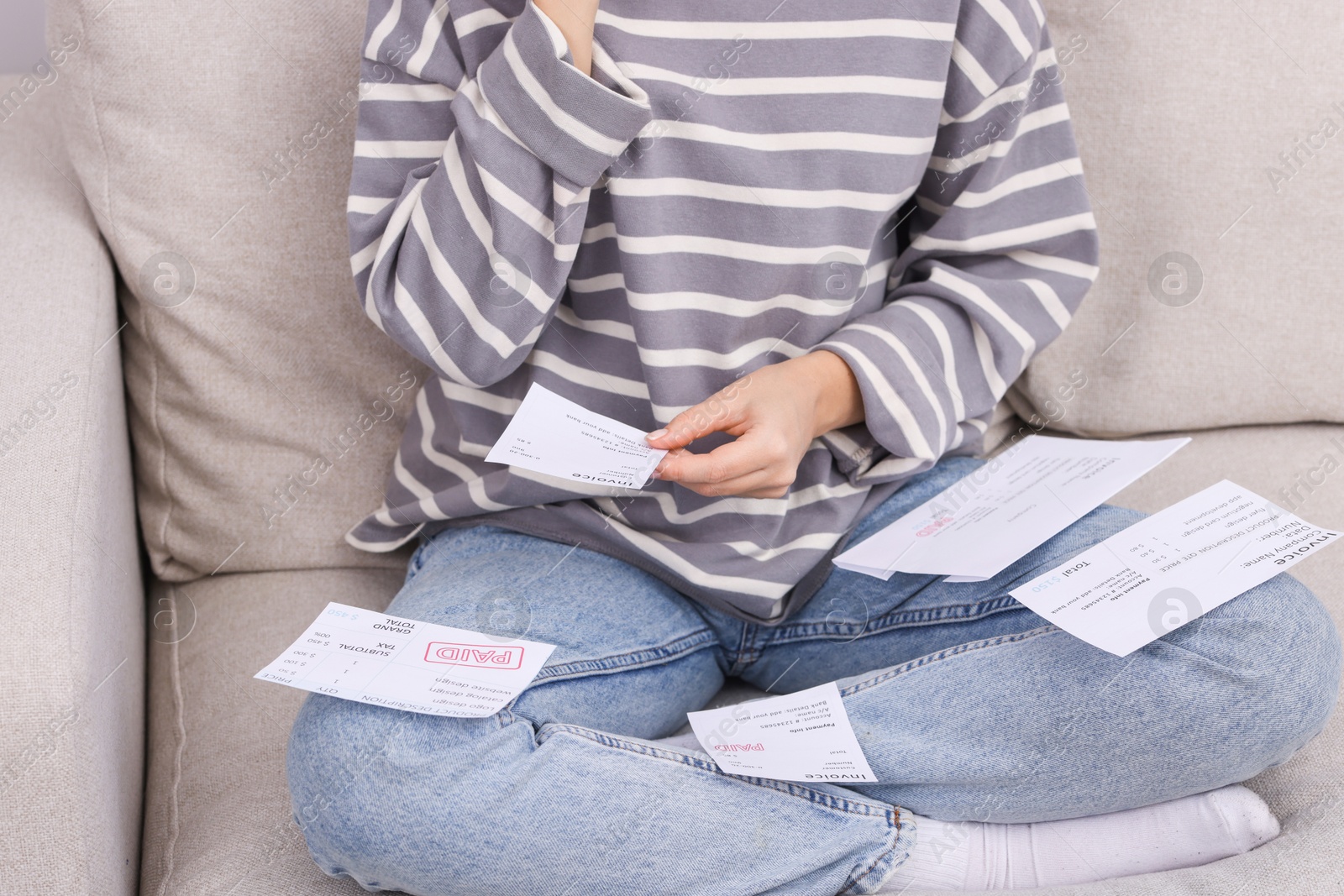 Photo of Paying bills. Woman with different invoices on couch at home, closeup