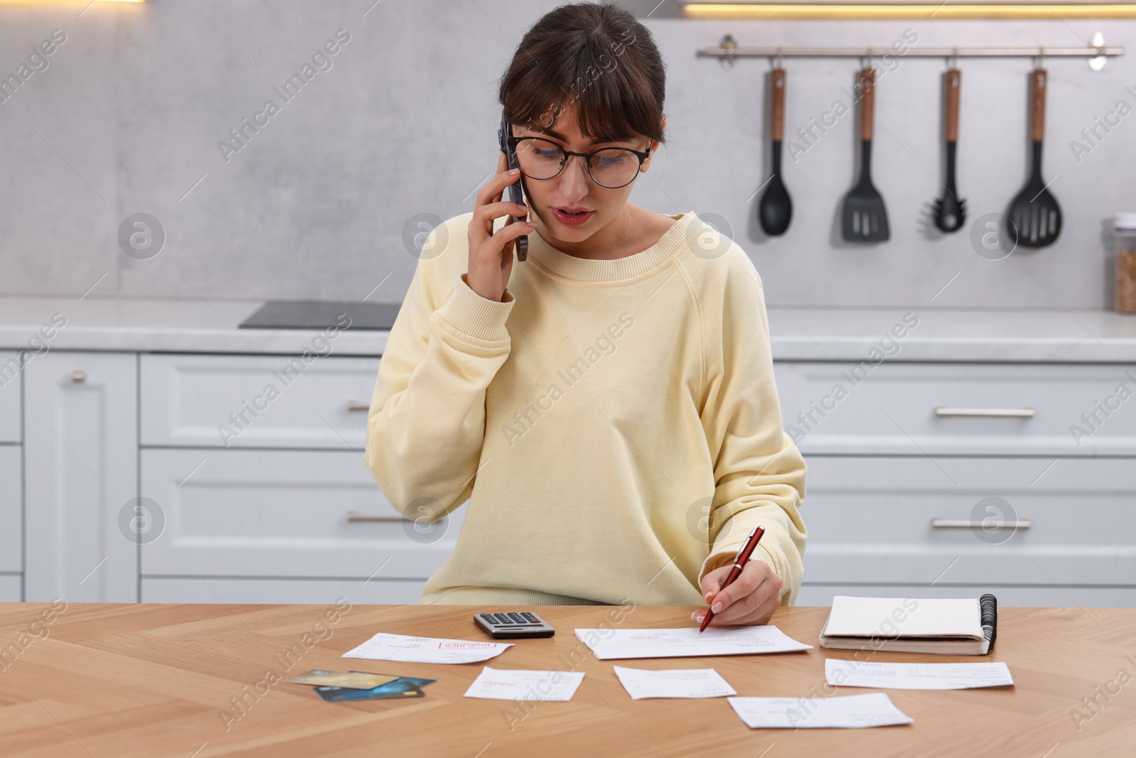 Photo of Paying bills. Woman with different invoices and calculator at wooden table indoors