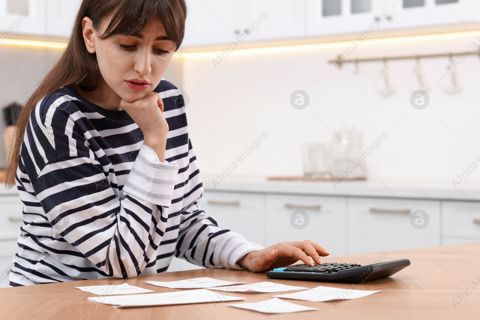 Photo of Paying bills. Woman with different invoices and calculator at wooden table indoors, space for text