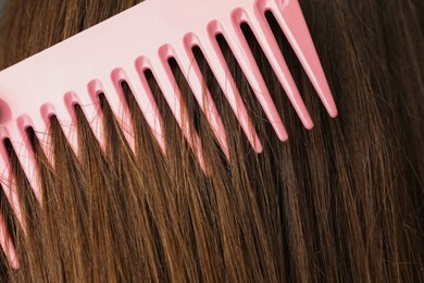 Photo of Brushing hair with plastic comb, closeup view