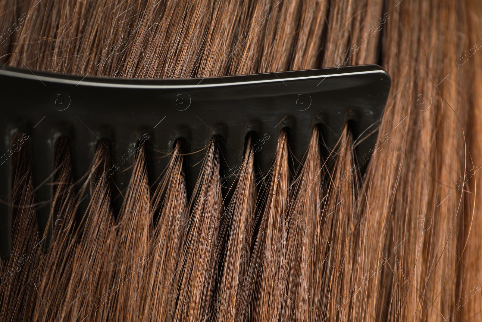 Photo of Brushing hair with plastic comb, closeup view